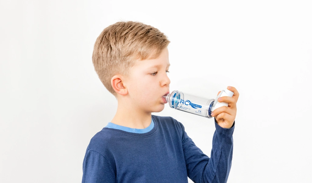 Ein Junge nutzt eine Inhalierhilfe f&uuml;r die Inhalation eines Dosieraerosols.
