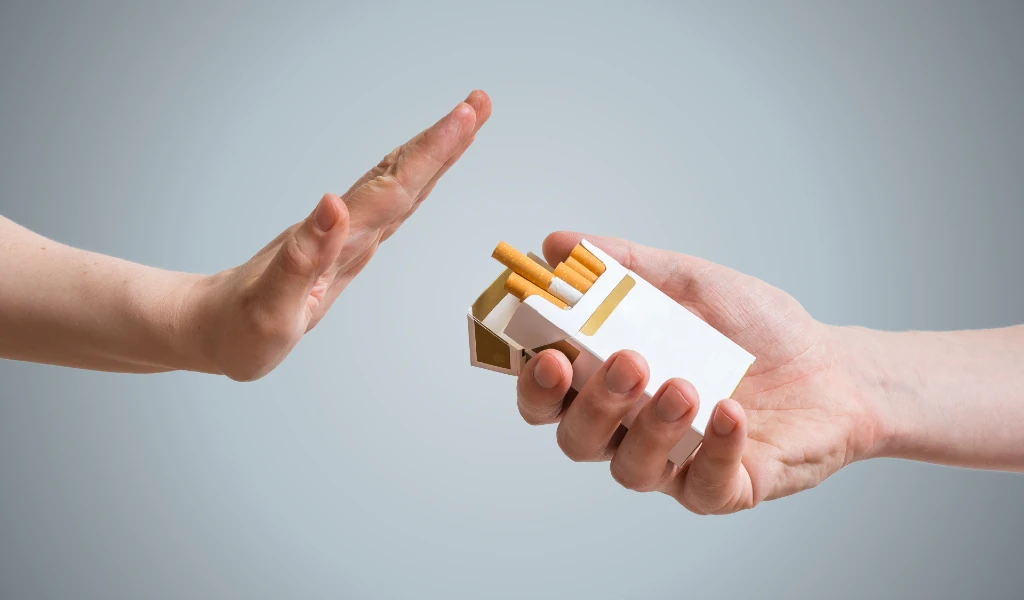 Eine Hand streckt sich aus, um ein Angebot von Zigaretten abzulehnen.